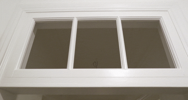 Дверная фрамуга белого цвета. Разделена на три равных стекла. Установлена в  дверном проёме старого фонда.