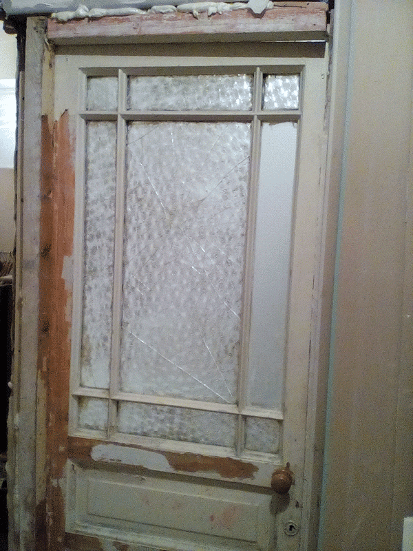 Фотография старой двери с ободраной краской и покосившейся коробкой. Требуется её замена. 