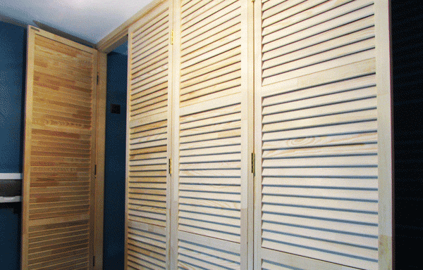 Фото деревянной перегородки которая сделана из жалюзийных дверей и является фасадом гардеробного шкафа.