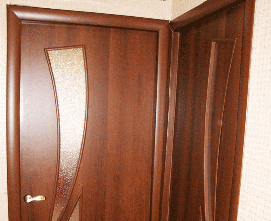 Две стандартные ламинированные двери в типовой многоэтажке. Ламинат в цвете орех, тёмно коричневого цвета.