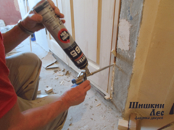 Процесс установки монтажной пены в щель между коробкой и стеной.